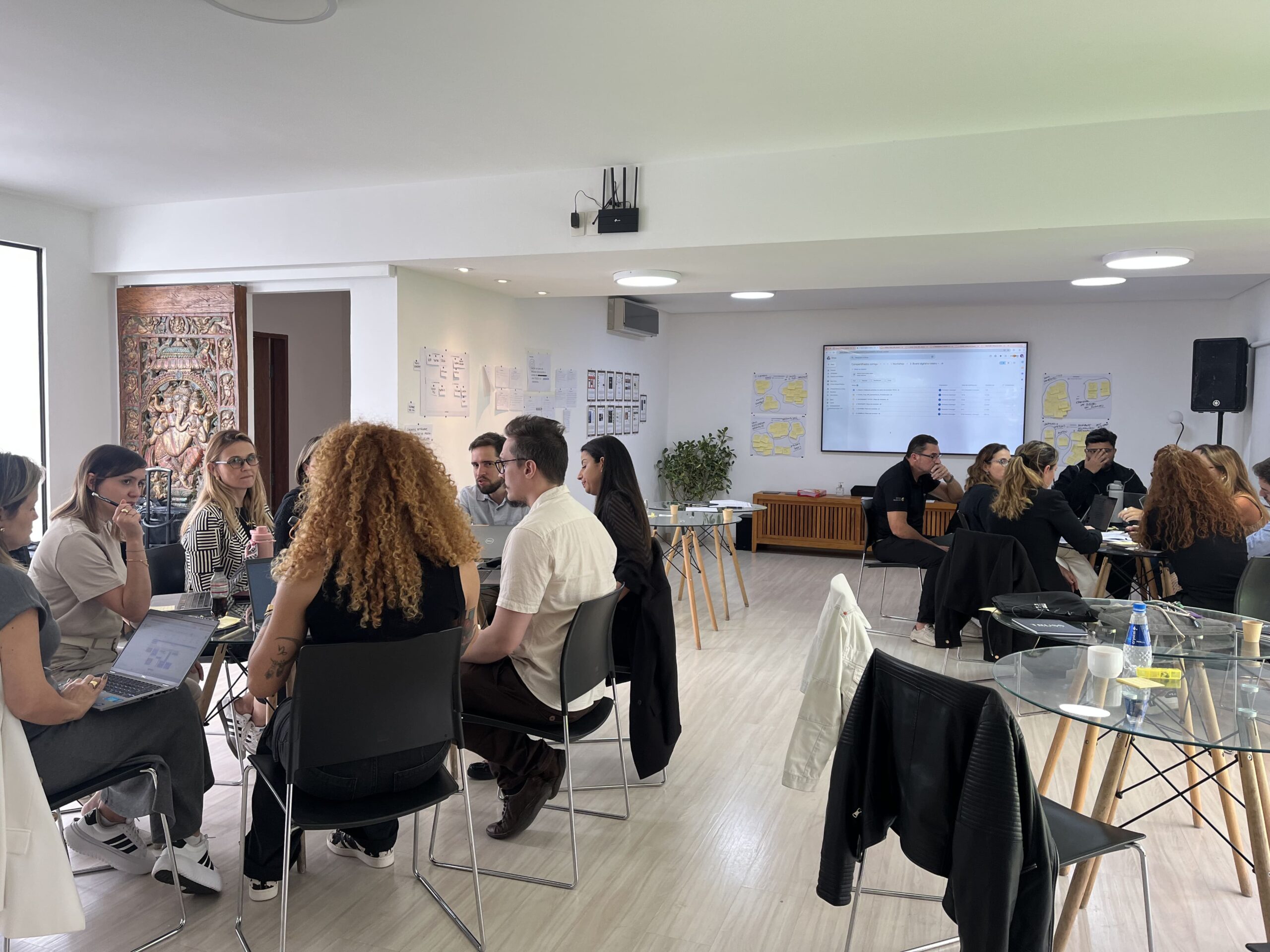 Participantes trabalham em grupos durante uma dinâmica colaborativa, analisando painéis com ideias e propostas para estruturar hubs e programas de inovação.